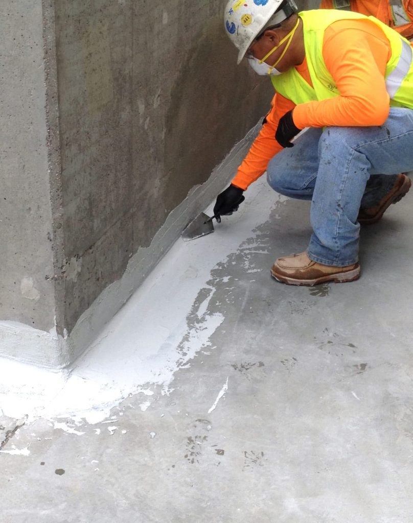 A contractor cementing the corners of a building as a way to waterproof corners. 