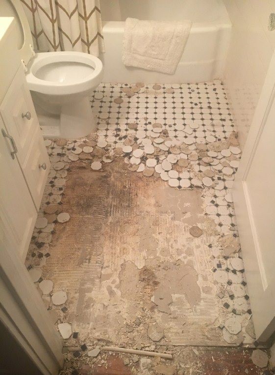 The expensive looking polka dot themed tiles of a toilet room's floor, removed and scattered around from an invasive, hacking waterproofing method. 