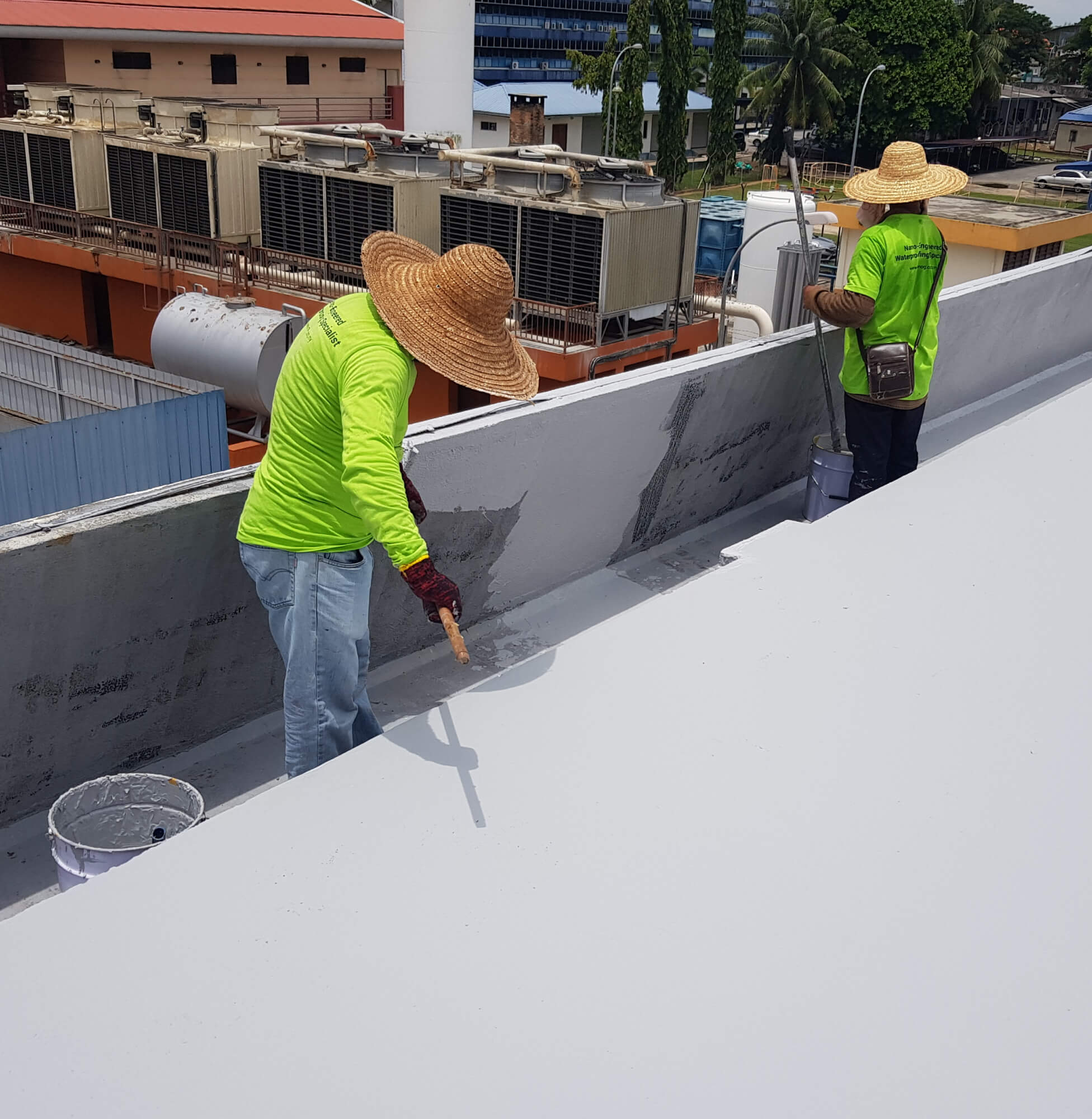 Workers applying Nano-G nanotechnology waterproofing solution on a building's rooftop.
