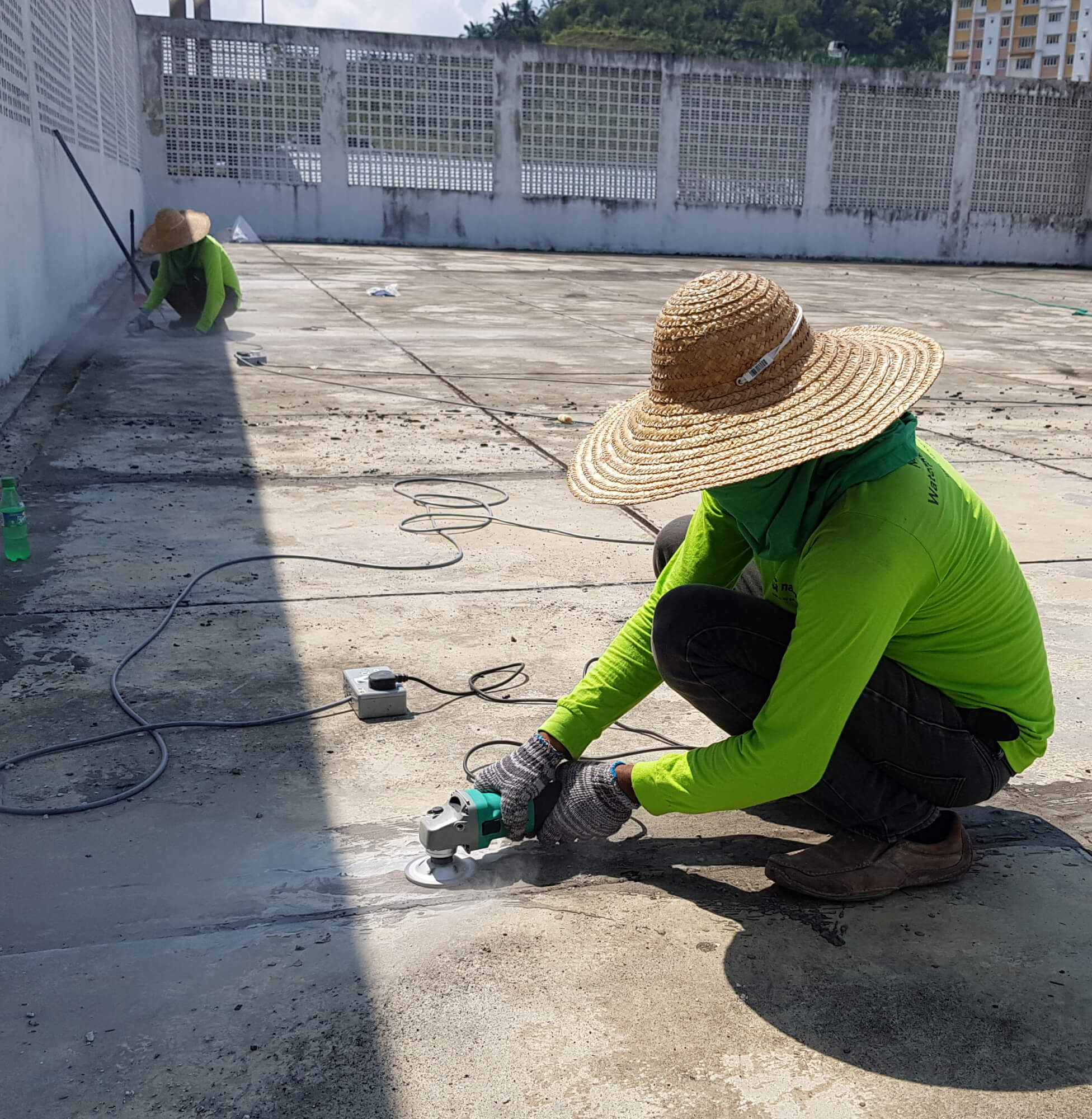Worker using tools to prepare a surface for Nano-G nanotechnology waterproofing solution on a rooftop.