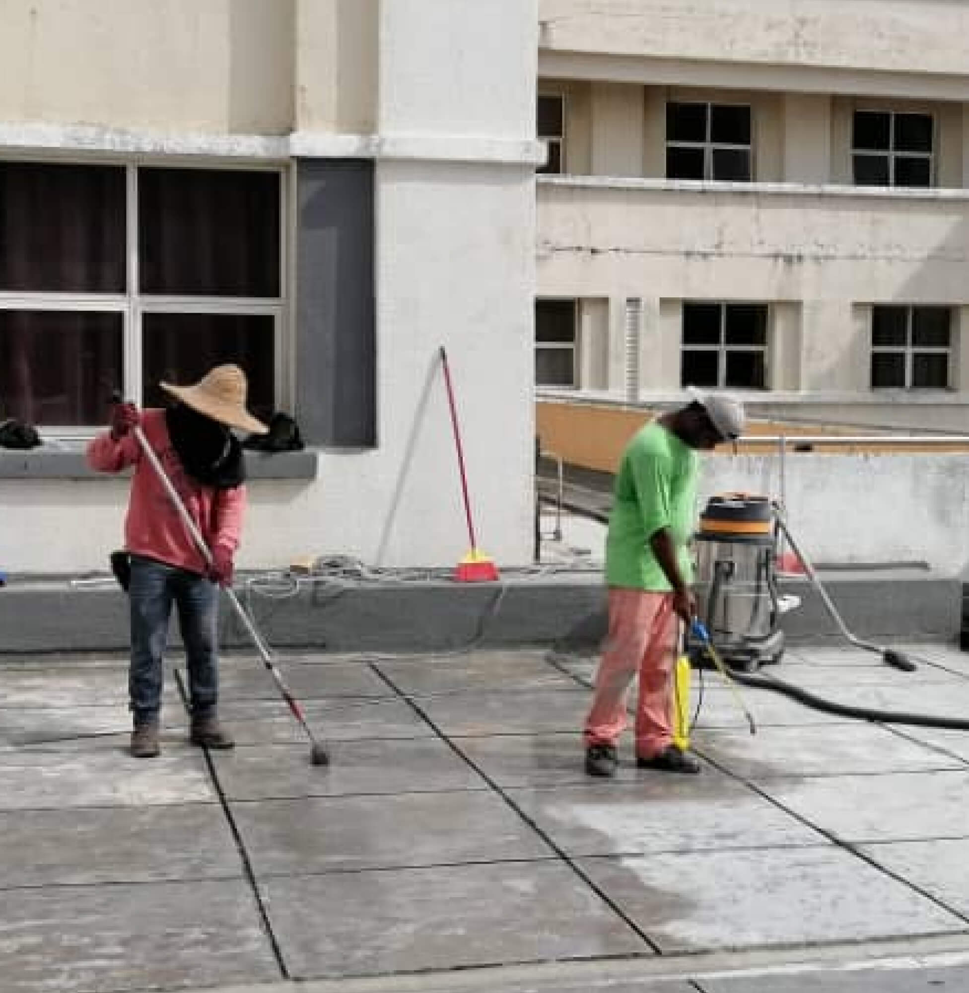 Workers applying Nano-G nanotechnology waterproofing solution on a rooftop.