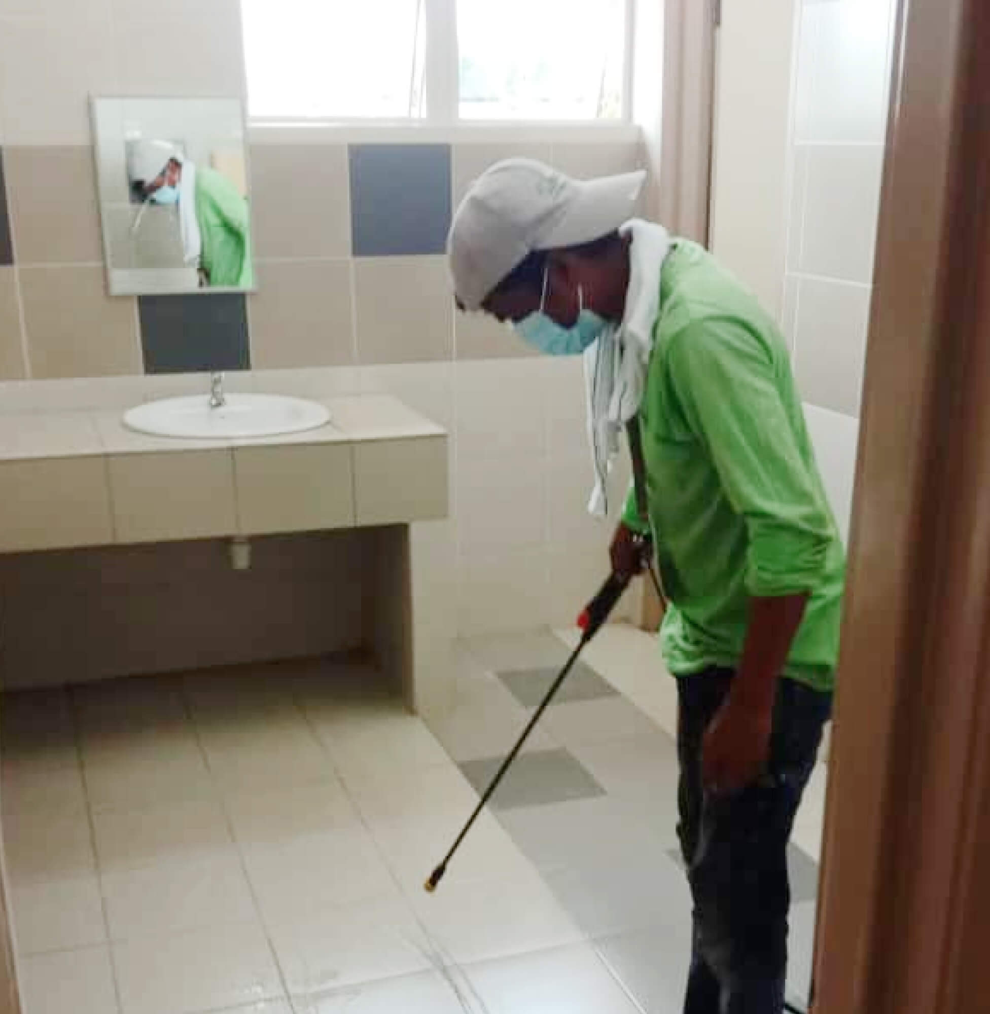 Worker applying Nano-G nanotechnology waterproofing solution in a bathroom.