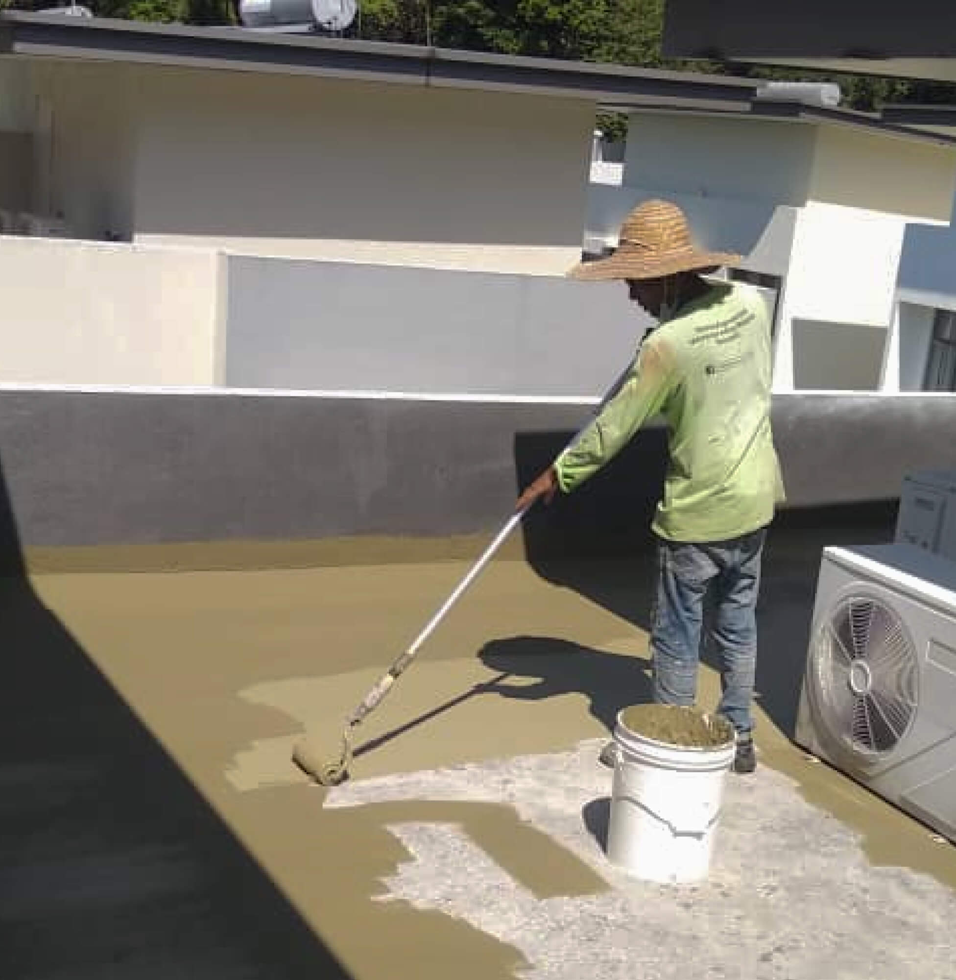 Worker applying Nano-G hospital-grade nanotechnology waterproofing solution on a rooftop.